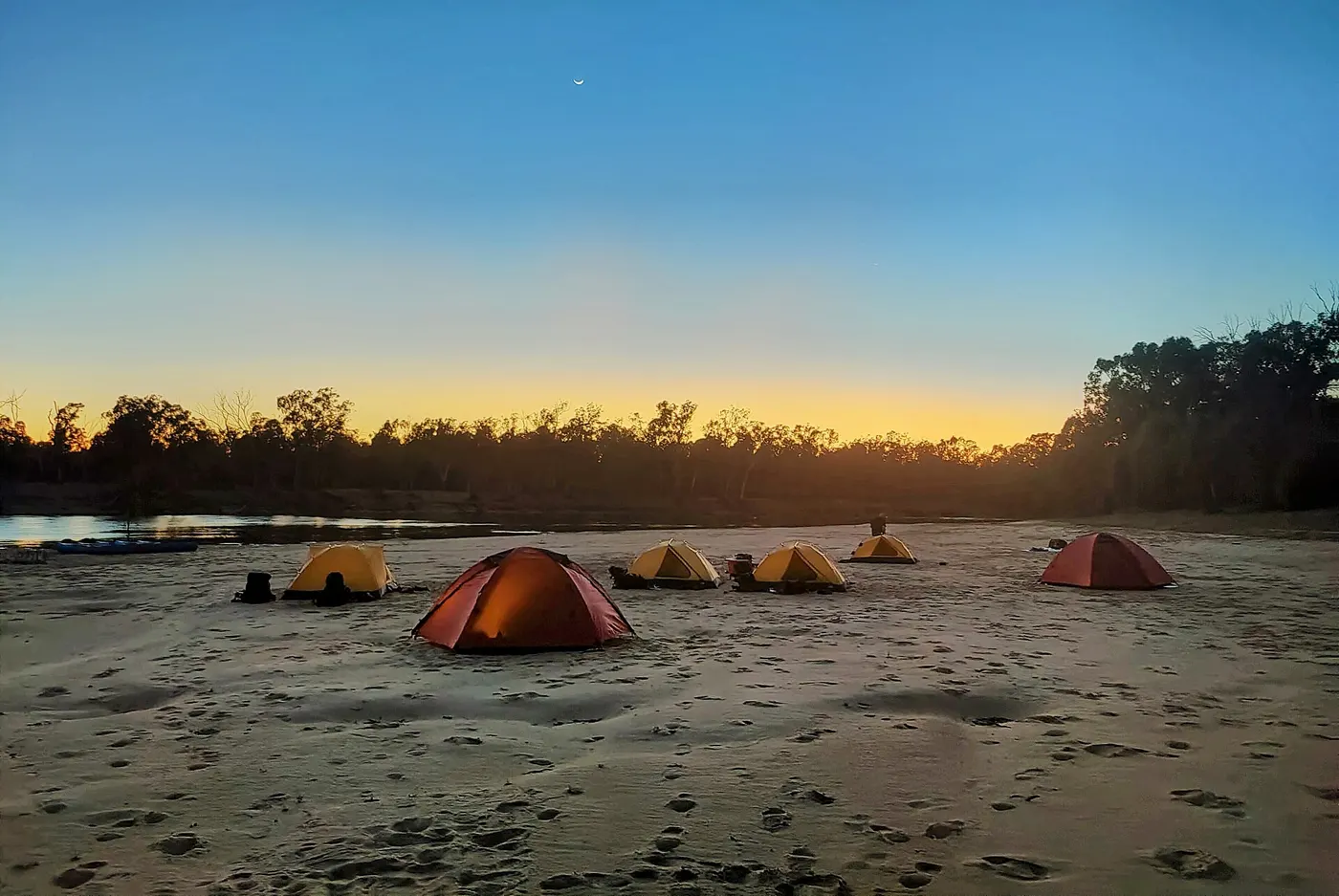 Tents on a sandy riverbank at sunrise beside the Murray River